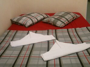 A bed with plaid bedding and two white towels folded on it. - Bambu Brasil Suites (Angra dos Reis)