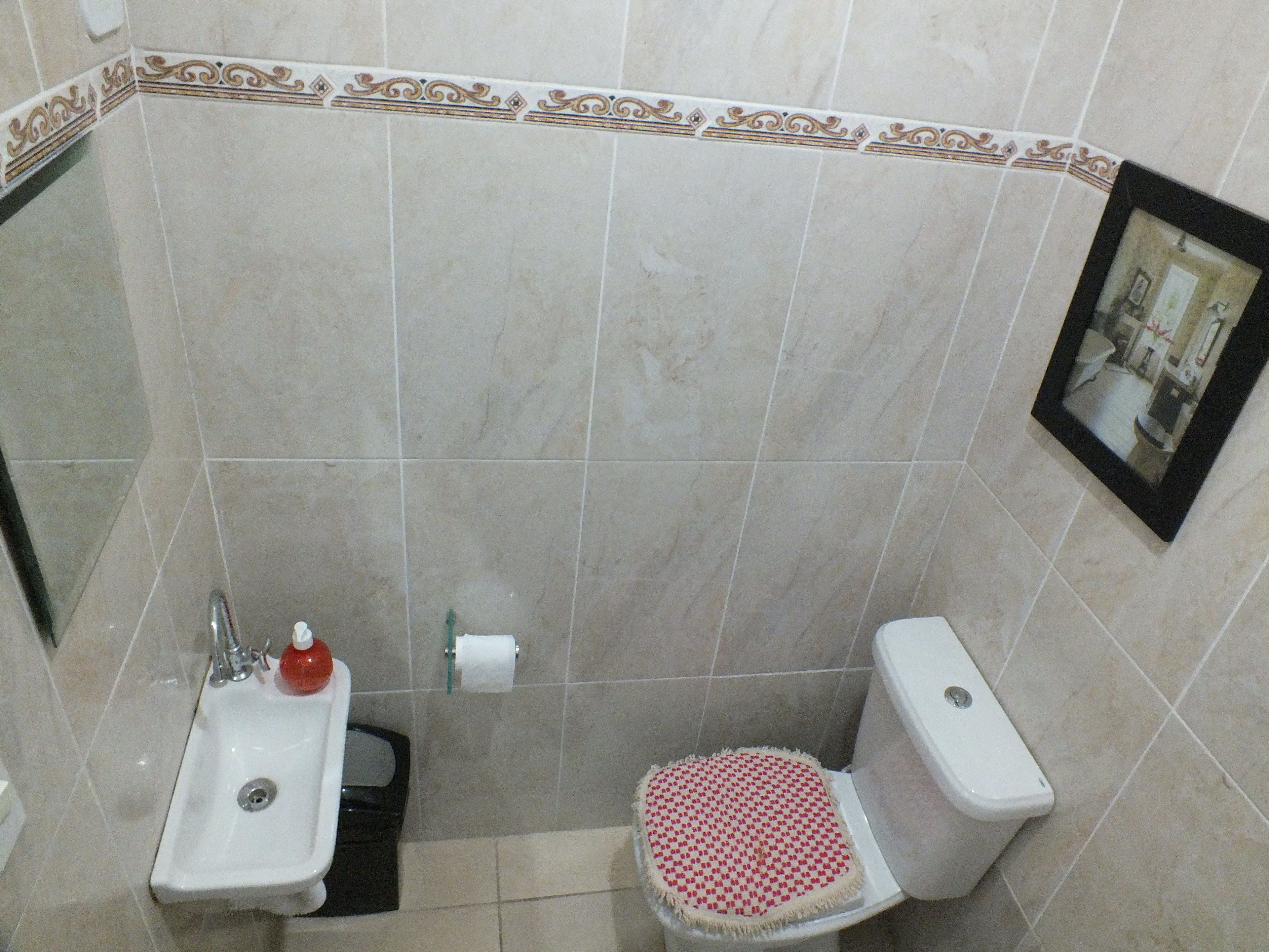 A bathroom with a sink, toilet, and a small trash bin.
