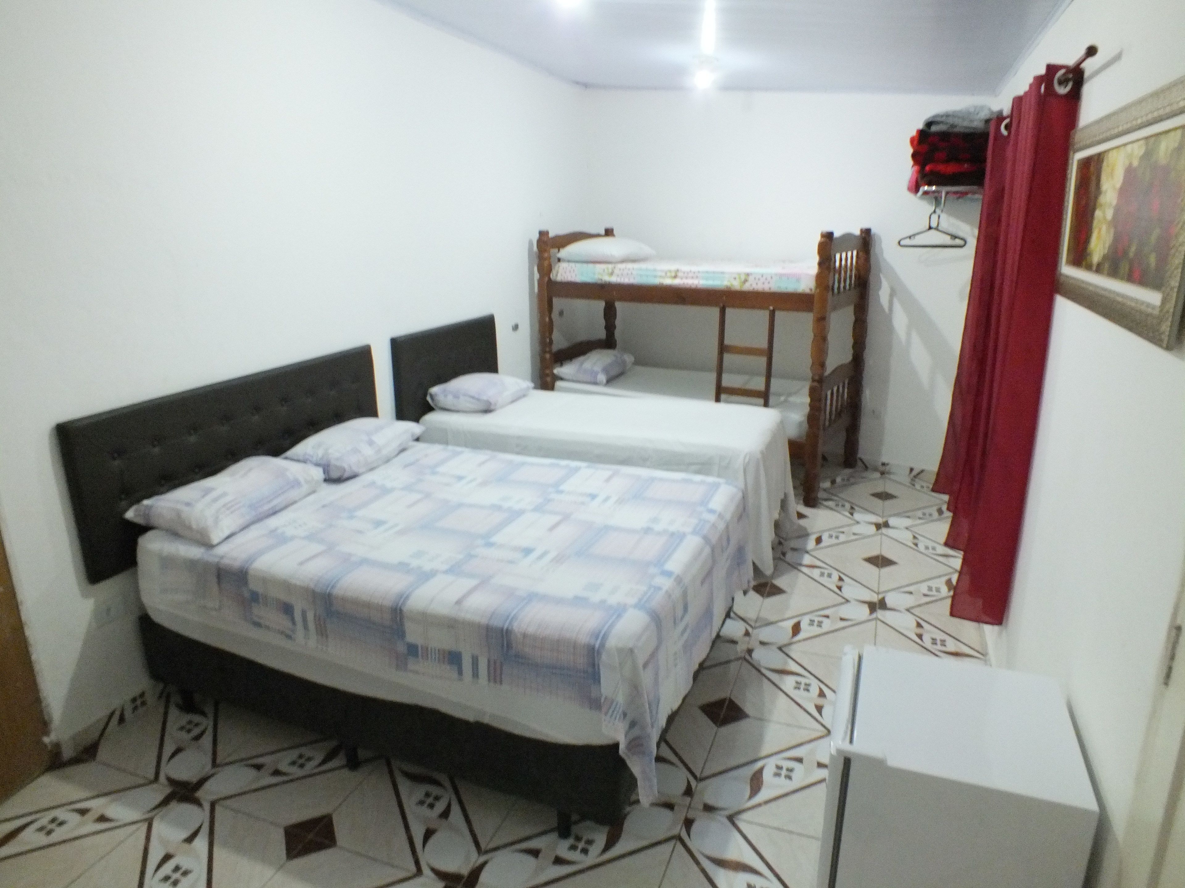 Un dormitorio con dos camas, un armario y suelo de baldosas.
