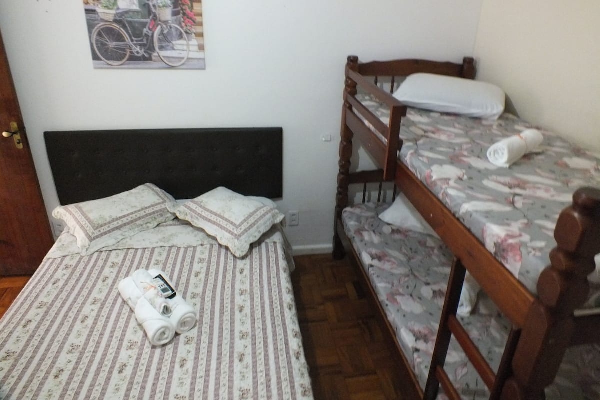 A room with a bed, a bunk bed, a wall-mounted picture, and a wooden door.