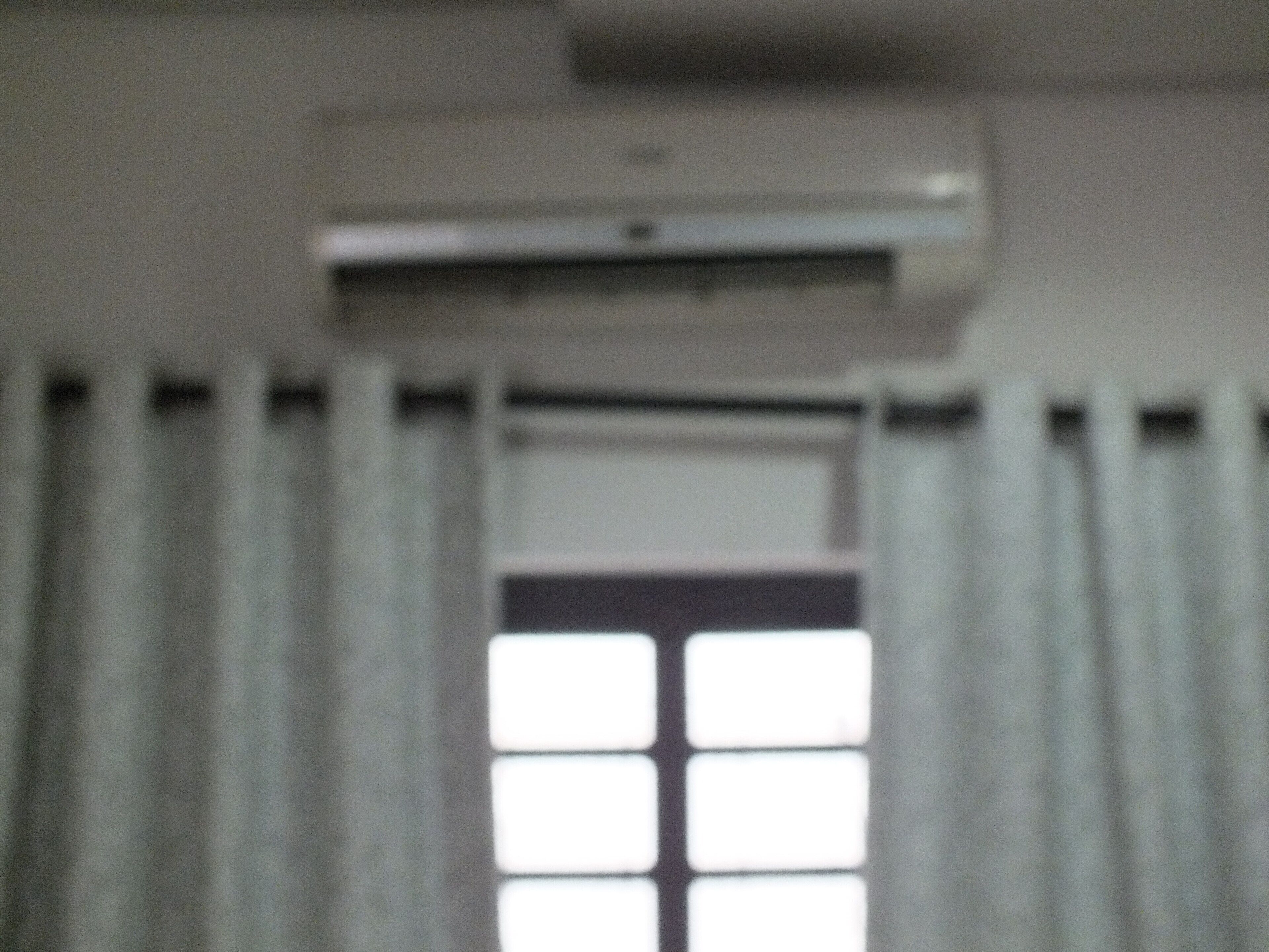 Eine Klimaanlage an der Wand über einem Fenster mit Blick ins Freie.