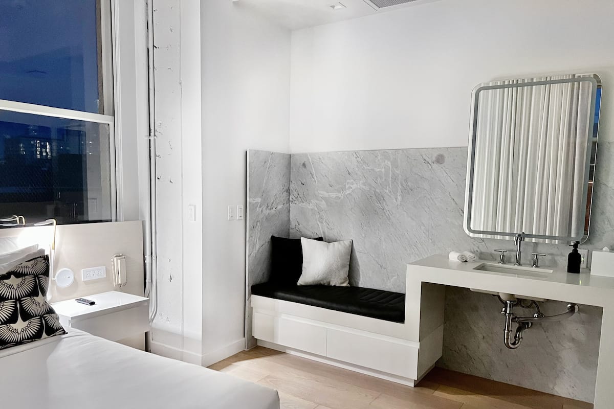 A modern bedroom with a bed, bedside table, and a built-in bench with a headboard.