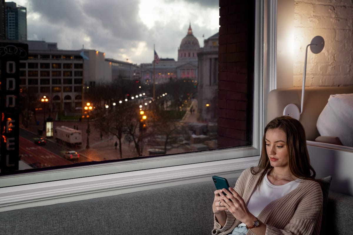 A person sitting by a window with a view of a cityscape, including a prominent building with a dome.