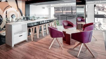 A modern office space with a glass partition, wooden flooring, and contemporary furniture.