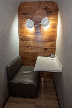 A corner room with a wooden accent wall, a small white table, and a leather bench.