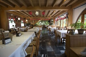 Un restaurante con varias mesas y sillas, suelo de baldosas y techo de madera.