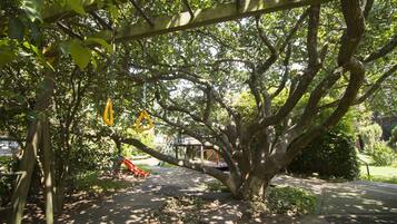 Un sendero arbolado con un parque infantil y una zona cubierta para sentarse.