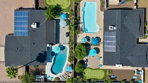 Un quartier résidentiel comprenant deux maisons, une piscine et des panneaux solaires.