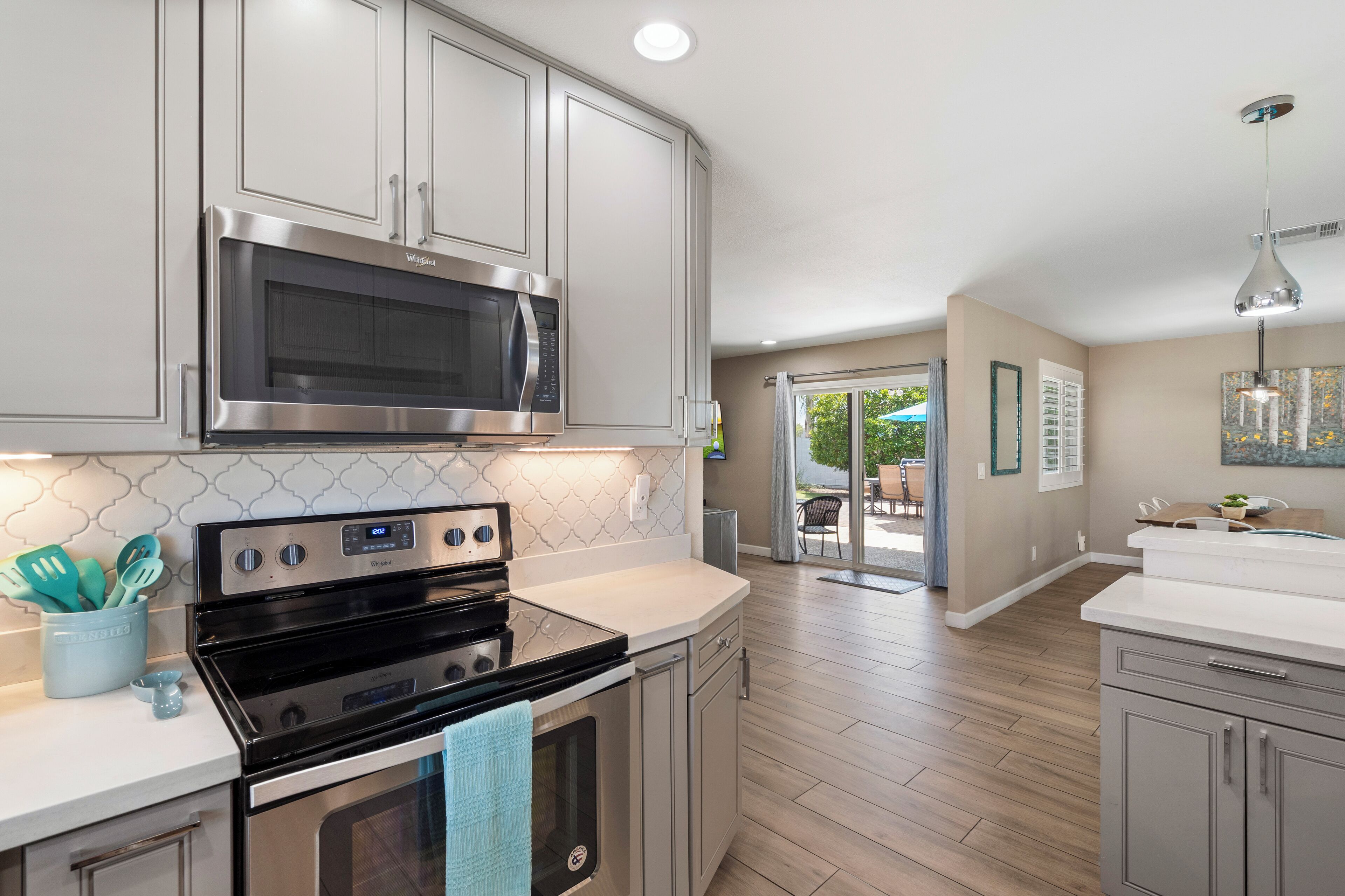A modern kitchen with stainless steel appliances, light-colored cabinetry, and a wooden floor.