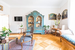 A room with a wooden floor, a blue cabinet with glass doors, a television on the wall, and a bed with a blue patterned bedspread. - Charme Foro Romano Luxury Terrace (Roma)