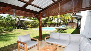 Un patio exterior con mesa de madera, dos sillas y un sofá.