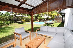 Eine Terrasse im Freien mit einem Holztisch, zwei Stühlen und einer Couch.