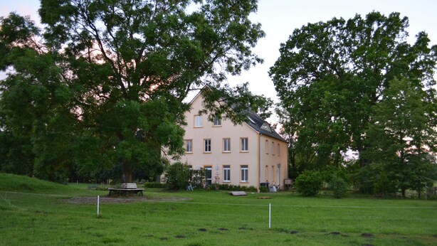 A two-story house with a symmetrical facade, surrounded by a well-maintained lawn and trees. - Pferdehof Muhlitz on Rügen, an idyll for individualists (Samtens)