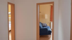 A hallway with a tiled floor leading to a room with a blue sofa and a lamp. - Pferdehof Muhlitz on Rügen, an idyll for individualists (Samtens)