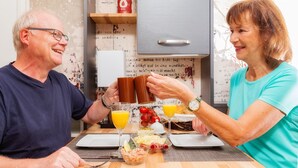 A dining table with breakfast items, a red oil can, and a wooden shelf in the background. - Achtern - Small but Nice: A small vacation home for 2 with a porch in Büsum (Büsum)