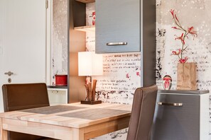 Ett modernt matområde med ett träbord, två stolar, en lampa och en dekorativ vas med blommor.