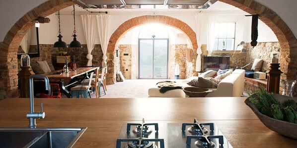 A spacious living area with a kitchen, dining area, and a large arched doorway leading to a balcony. - Tuscany romance. Rural charm between Montalcino and sea. Relax pur (Cinigiano)