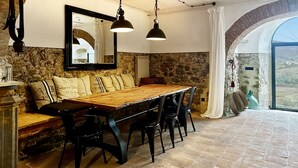 A rustic dining area with a wooden table, black chairs, and a stone wall. - Tuscany romance. Rural charm between Montalcino and sea. Relax pur (Cinigiano)