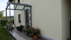 A building with a covered entrance, potted plants, and a visible door. - Wonderful view of the Nahe Valley and the Frombork (Sonnenberg-Winnenberg)