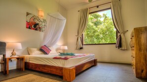 Un dormitorio con cama de madera, lámparas de noche, mosquitero y ventana con cortinas.