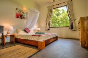 Un dormitorio con cama de madera, lámparas de noche, mosquitero y ventana con cortinas.