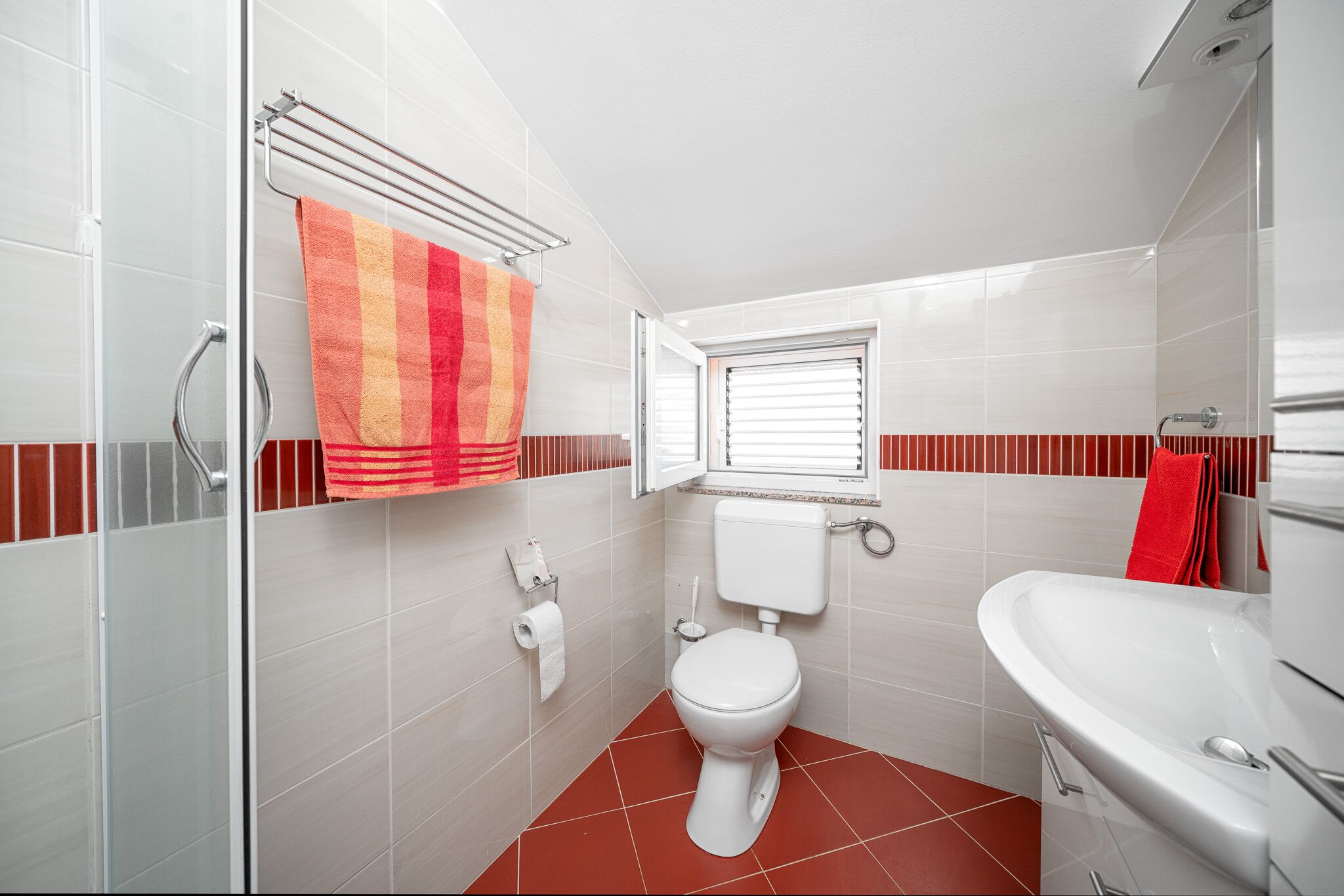 A bathroom with a toilet, a shower, and a sink.