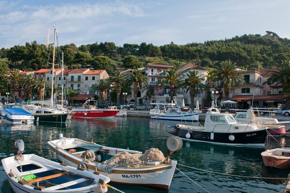 A marina with various boats docked, surrounded by residential buildings and palm trees. - Last minute for June - romantic villa with pool and BBQ, 6 min from the sea (Podgora)