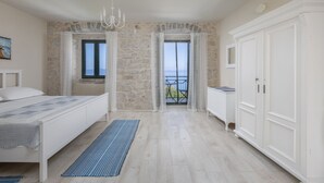 A bedroom with a bed, a wardrobe, a chandelier, and a view of the sea through a window. - Last minute for June - romantic villa with pool and BBQ, 6 min from the sea (Podgora)