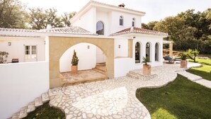 Un bâtiment blanc avec un toit en tuiles, des marches en pierre et une terrasse dallée.