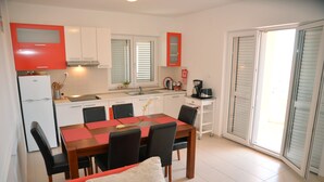 A compact kitchen with white cabinets, a red refrigerator, and a dining area with a wooden table and chairs. - Villa Flipa with pool Ap. Ema (Vodice)