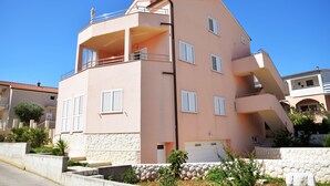 A multi-story building with balconies, a stone base, and a clear blue sky. - Villa Flipa with pool Ap. Ema (Vodice)