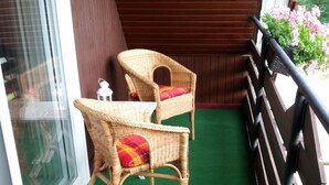 Ein Balkon mit zwei Korbstühlen, einem kleinen Tisch und einem Blumentopf.