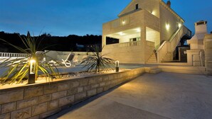 Une maison moderne dotée d’une piscine, de murs en pierre et d’un escalier menant à l’étage supérieur.