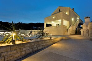 Ein modernes Haus mit Pool, Steinmauern und einer Treppe, die zum Obergeschoss führt.