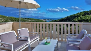 Un balcon avec des chaises blanches, une table et un parasol blanc.
