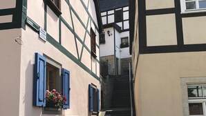 Una estrecha calle empedrada bordeada por edificios tradicionales con entramado de madera y contraventanas azules.