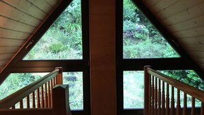 Una habitación con techo inclinado y ventanas amplias que ofrecen vistas de exuberante vegetación.