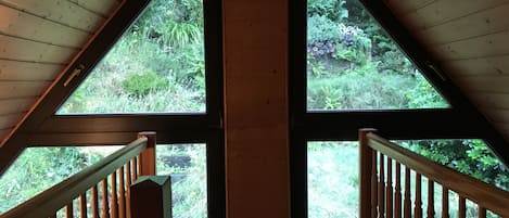 Una habitación con techo inclinado y ventanas amplias que ofrecen vistas de exuberante vegetación.