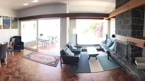 A spacious living area with a wooden herringbone floor, a fireplace, a sofa, and a dining area with a table and chairs. - Sea view with a view  (Canico)