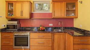 A kitchen with wooden cabinets, a microwave, an oven, a sink, and a fruit bowl on the counter. - Modernly designed vacation home on a 40000 m² finca in a secluded location (Tenerife)