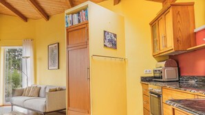 A compact kitchen with wooden cabinets, a built-in oven, and a refrigerator. - Modernly designed vacation home on a 40000 m² finca in a secluded location (Tenerife)