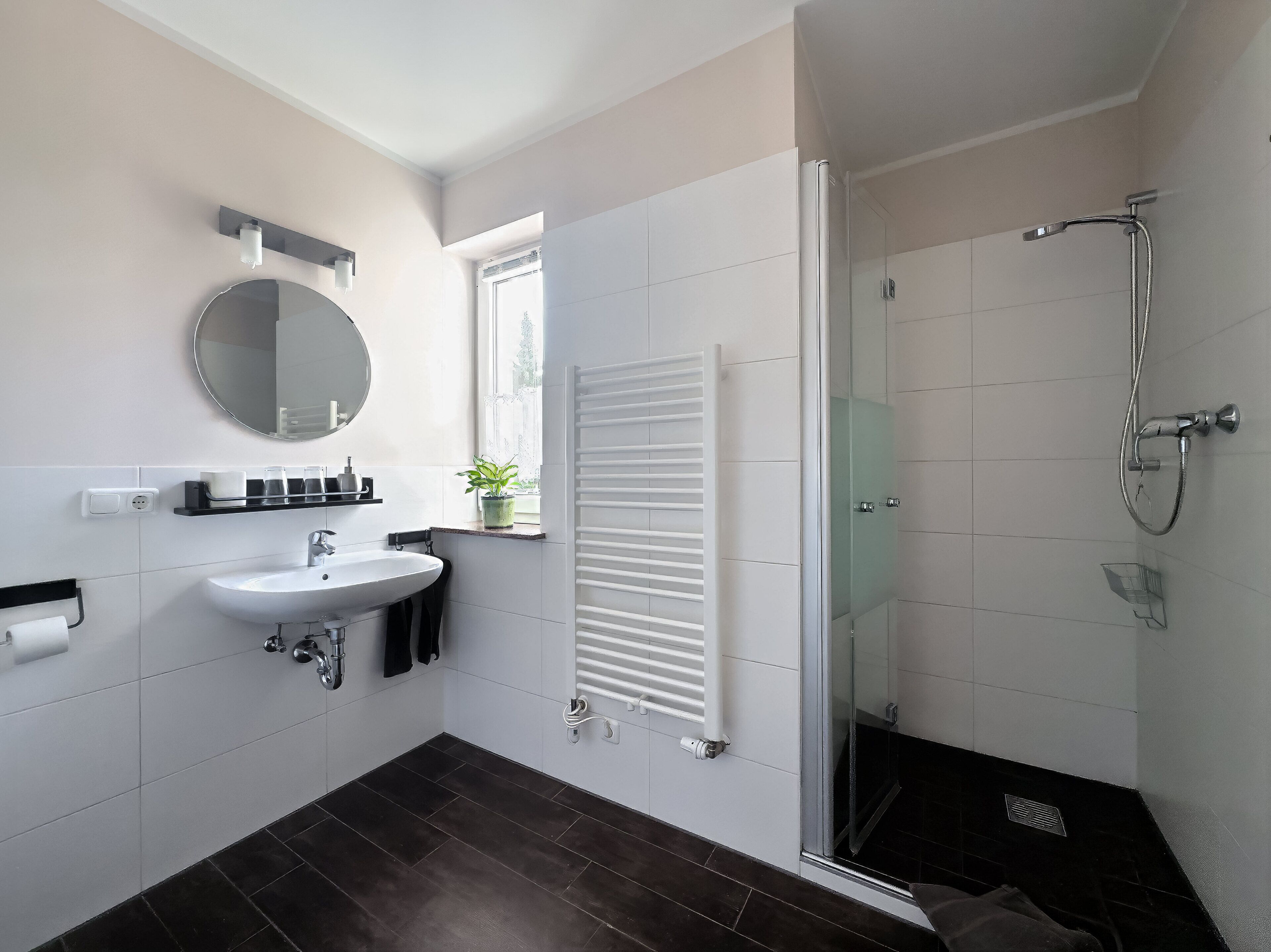 Un baño moderno con lavamanos, espejo, toallero y cabina de ducha de vidrio.