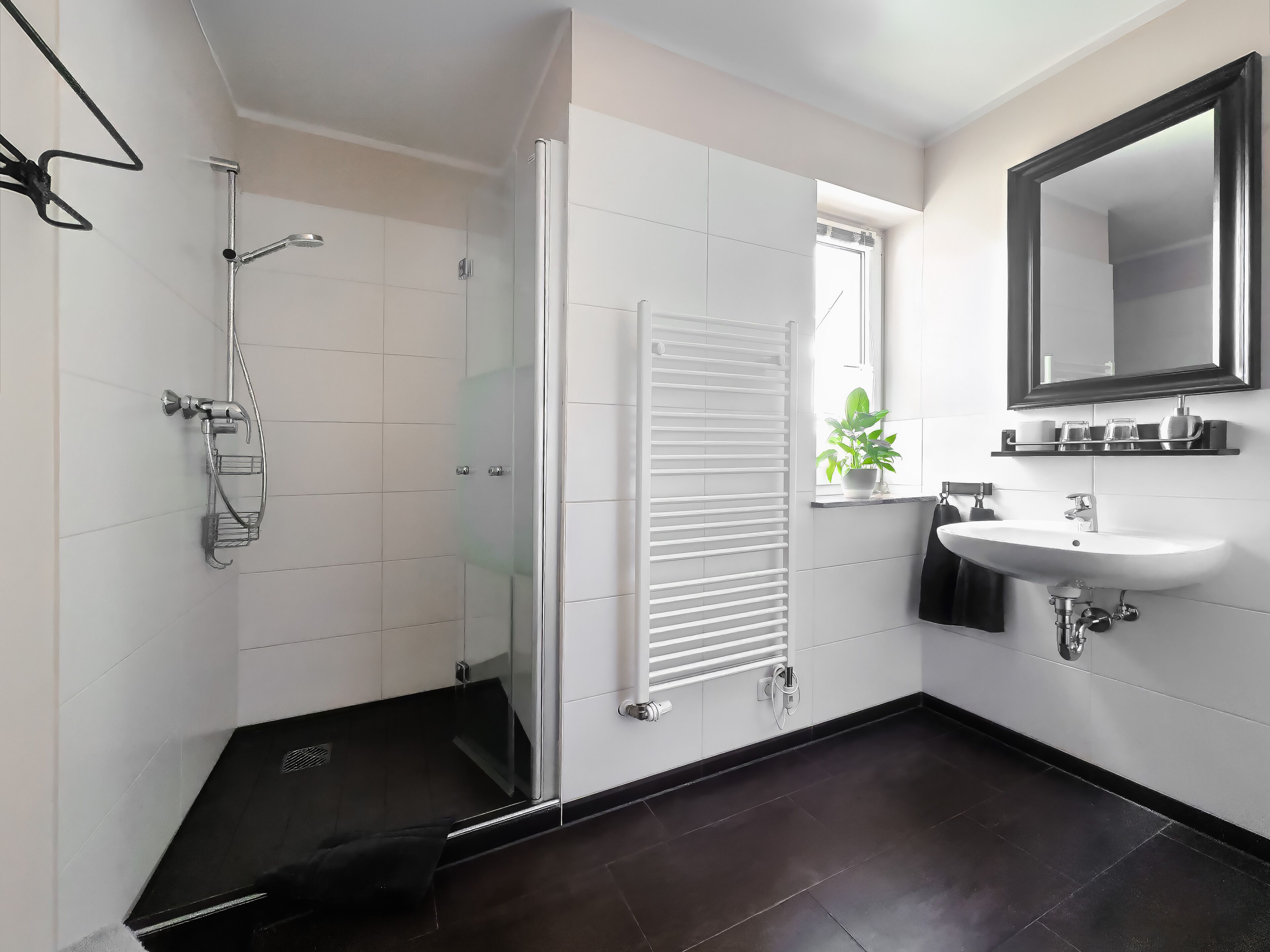 Une salle de bain moderne équipée d’une douche, d’un porte-serviettes, d’un lavabo et d’un miroir.