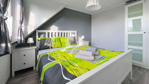 A bedroom with a bed, nightstands, a lamp, a window with curtains, a ceiling light, and a wardrobe. - Ferienhaus Kaiserhof (Markkleeberg)