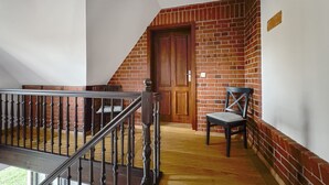 A staircase with a wooden railing, a brick wall, and a wooden door. - Ferienhaus Kaiserhof (Markkleeberg)