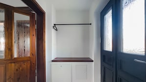 A hallway with a wooden door, a white wall, a black door, and a window with frosted glass. - Ferienhaus Kaiserhof (Markkleeberg)