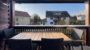 A wooden deck with a table and chairs, overlooking a residential area with houses. - Ferienhaus Kaiserhof (Markkleeberg)