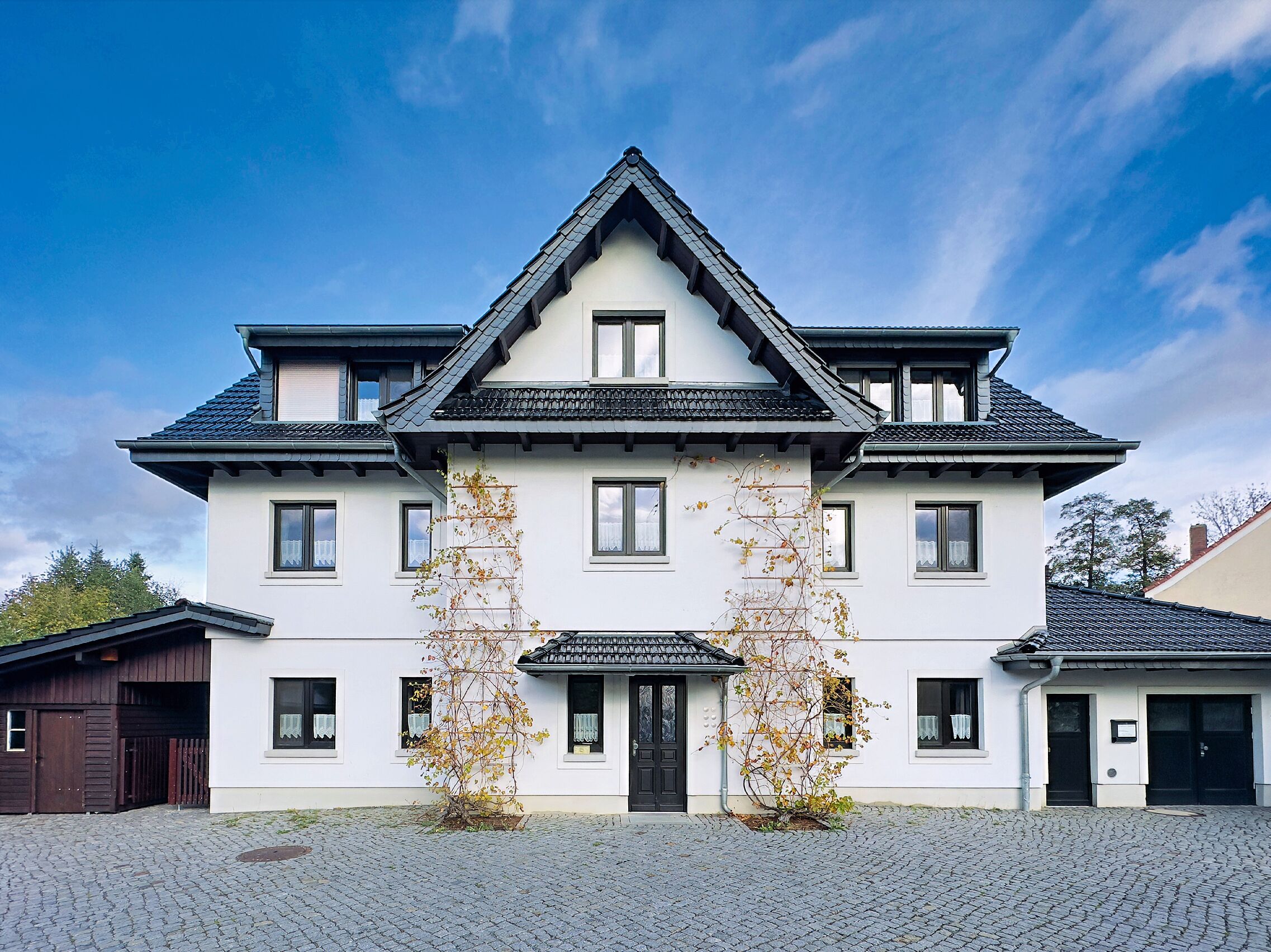 Ein zweistöckiges Gebäude mit einer symmetrischen Fassade, einem zentralen Eingang und einem Ziegeldach.