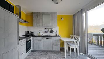 A modern kitchen with grey cabinets, a white countertop, and a dining area with a white table and chairs.