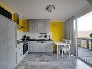 A modern kitchen with grey cabinets, a white countertop, and a dining area with a white table and chairs.